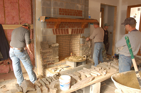 Shown is the installation of firebox surrounds using adhered masonry veneer units. Credit: Image courtesy of Keiger Masonry